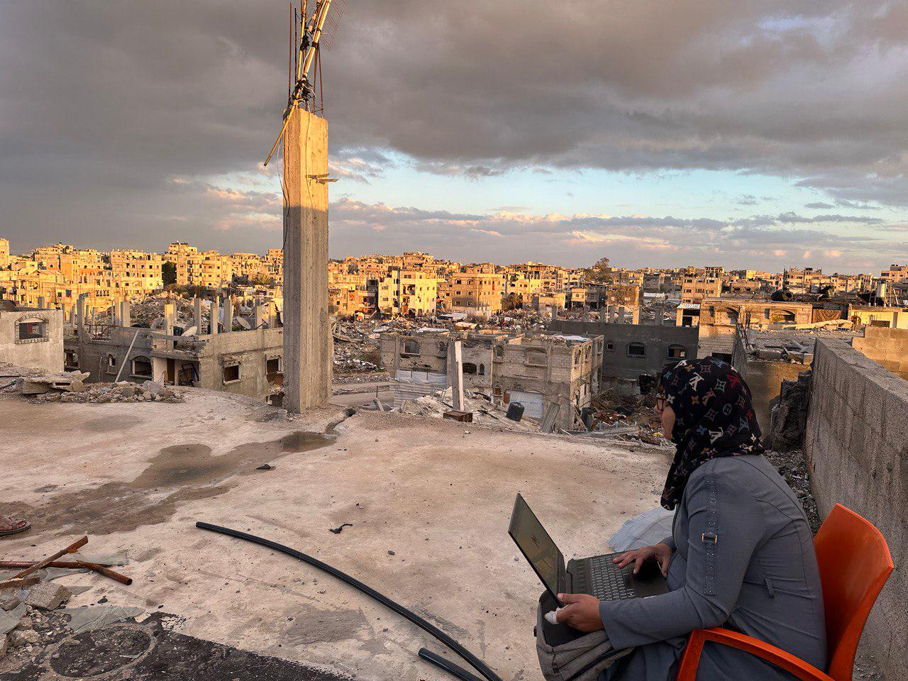 Gaza 40 student on a laptop at a roof top, trying to get an internet signal